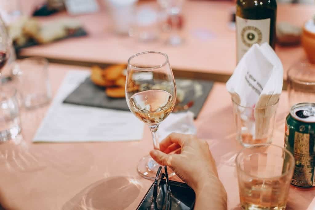 Person Holding Wine Glass Near Clear Shot Glasses